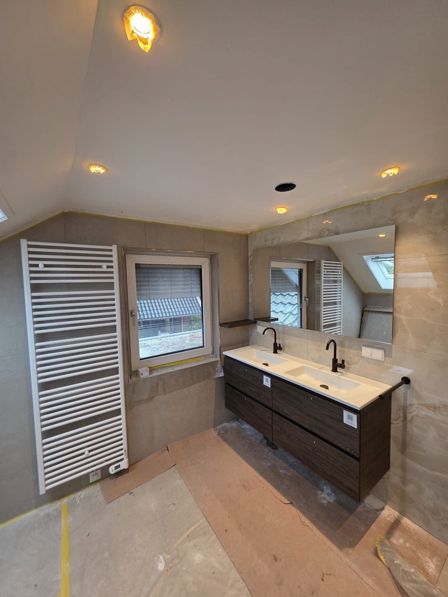 Badkamer met dubbel wastafelmeubel en handdoekradiator in Almelo