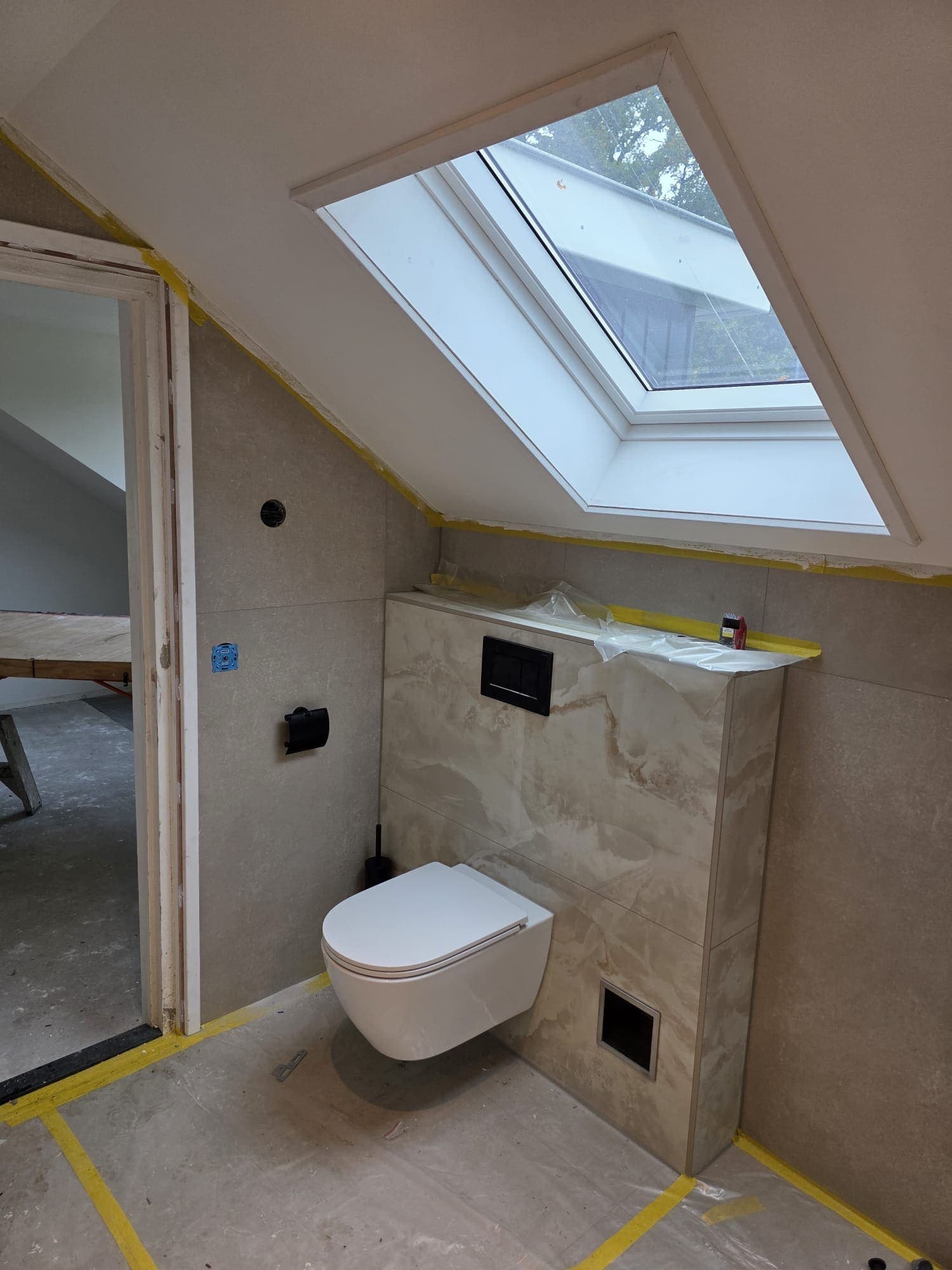 Hangtoilet met inbouwreservoir onder een dakraam in een badkamer in Almelo