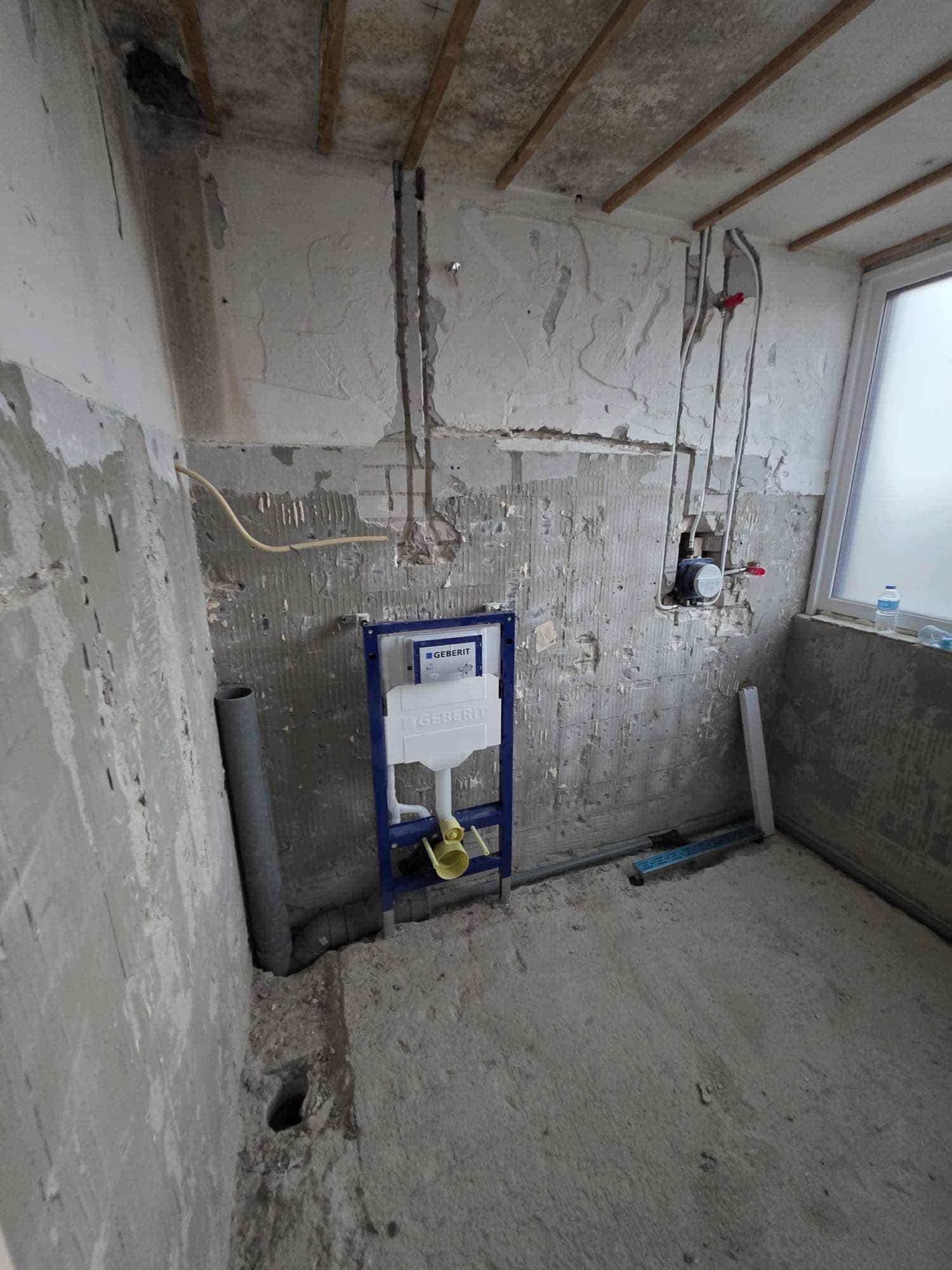 Ruwbouw van een badkamer met douchegoot en inbouwreservoir in Almelo
