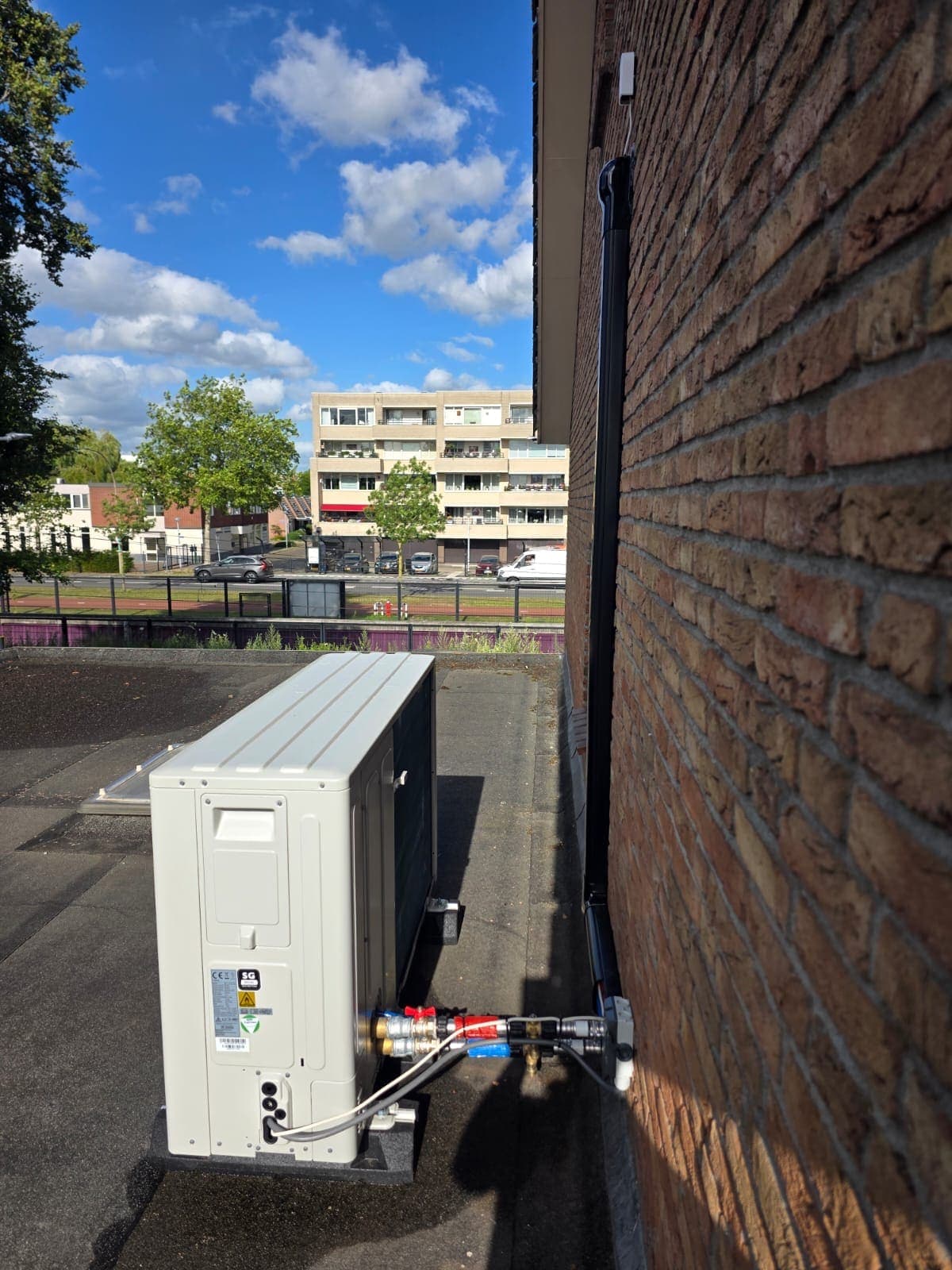 Buitenunit van een warmtepomp tegen de gevel van een appartement in Almelo
