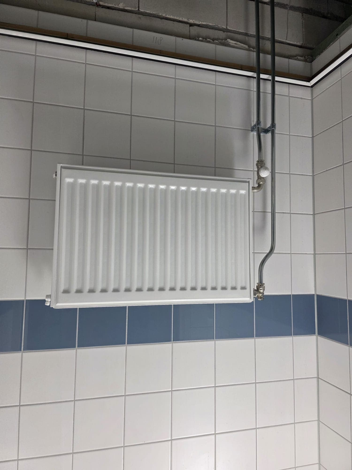 Vervangen radiator tegen betegelde wand in een badkamer in Almelo