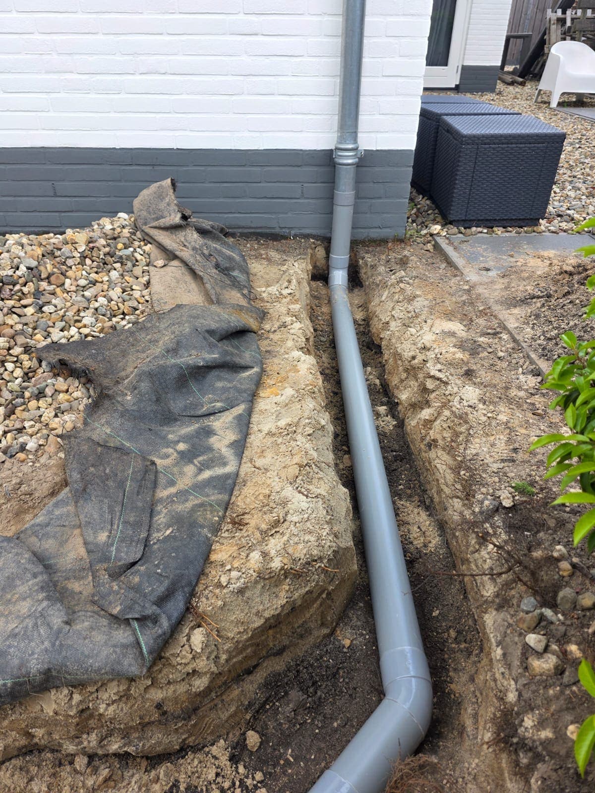 Nieuwe rioolleiding in een sleuf in de tuin bij een woning in Almelo