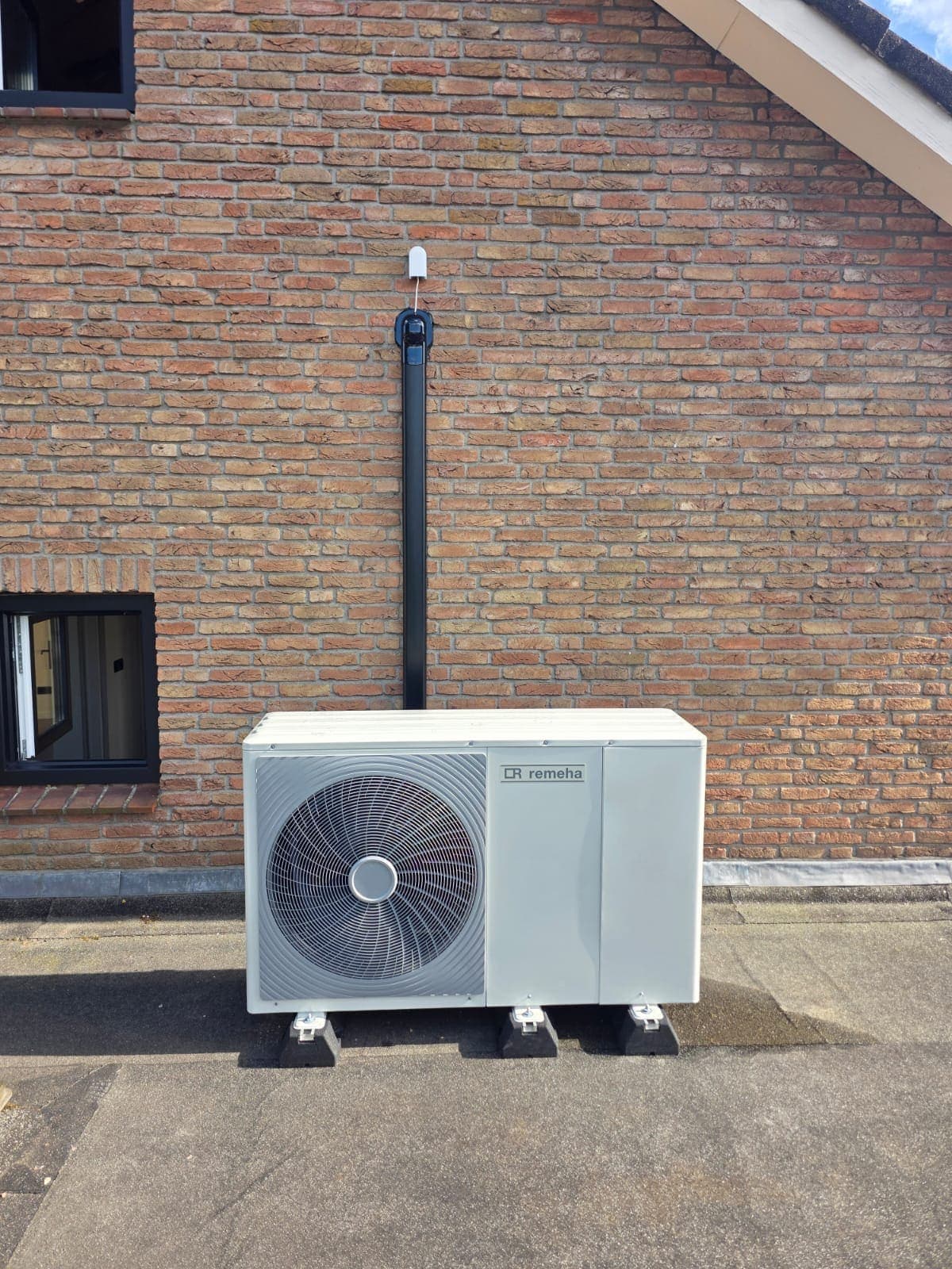 Buitenunit van een warmtepomp tegen de gevel van een woning in Almelo